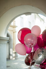 Bunte Luftballons für eine Hochzeitsfeier, im Hintergrund eine Fassade in Unschärfe.