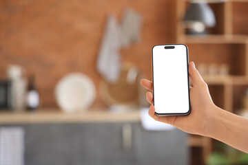 Woman with blank mobile phone in kitchen, closeup