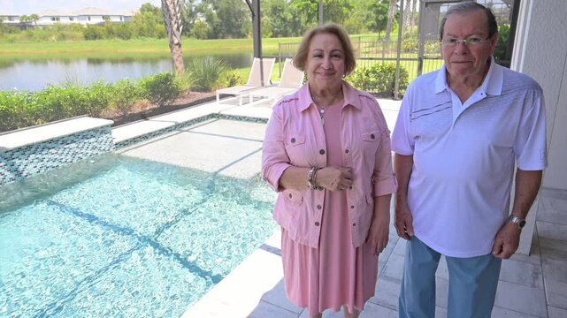 mature couple are happy with their beautiful new tile job on their outdoor pool and show their customer happiness with the thumbs up sign