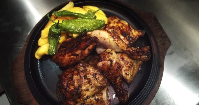 Beautiful slow motion, overhead angle shot of a charcoal roasted chicken dish with fries and padron bell pepper.
