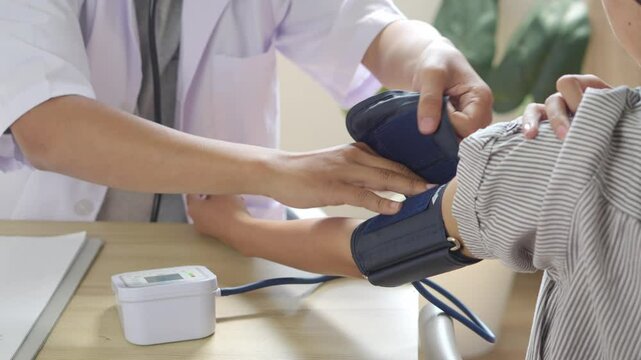 Male Doctor Measuring Arterial Blood Pressure Of Patient Girl Using Cuff, Write Note And Checking With Stethoscope