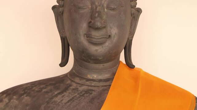 Close up of Buddhist statue with orange kasaya, Wat Pho temple, Bangkok