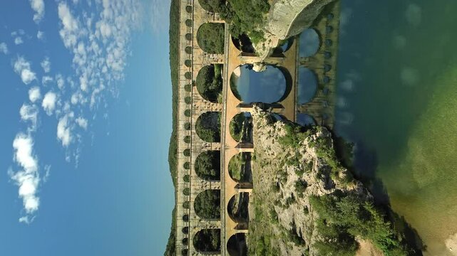 Vertical aerial shot of Aqueduc de Roquefavour with river during sunny day in France. Backwards shot.