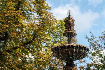 The working bronze fountain splashes water in the Volodymyrska Hirka (Saint Volodymyr Hill) Park in Kyiv, Ukraine, during the late summer or early autumn. 