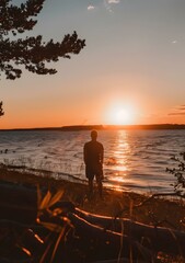 Fototapeta premium Silhouette of a Man Standing at the Beach During Sunset