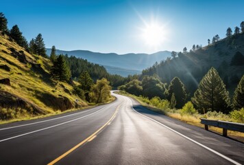 Naklejka premium Winding Asphalt Road Through Mountainous Landscape with Sunlight