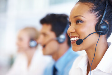 Woman, talking and smile in call center for customer service, telemarketing and FAQ in office. Female agent, contact or headset at help desk with team, communication or bilingual consultant with tech