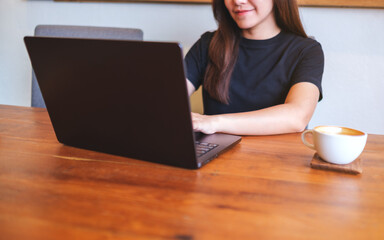 Fototapeta premium Closeup image of a young woman working and typing on laptop computer at home