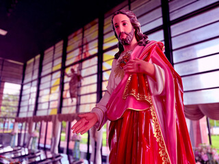 statue of Jesus Christ, draped in red and white garments, displayed inside a beautifully lit church...