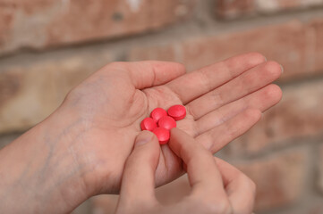 Kobieta zażywająca leki przeciwbólowe w postaci czerwonych pigułek 