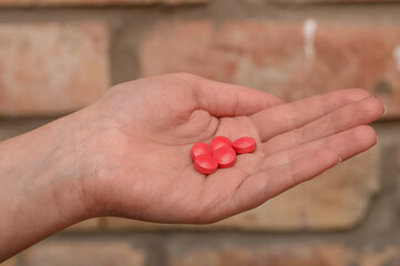 Ręka pełna czerwonych lekarstw, nałóg, narkomania