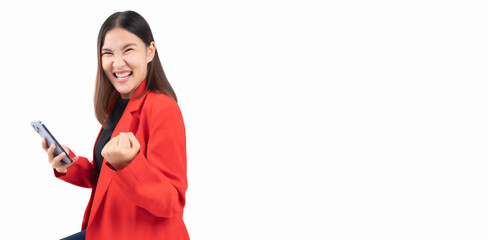 Cheerful business Asian young woman celebrates while holding a smartphone, conveying success and positivity She get excitement, ideal for concepts related to achievement, technology and communication