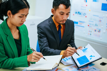 A group of professional business men and women are having a constructive meeting, discussing strategies, exchanging ideas and making decisions in a modern organization. They are wearing formal suits.
