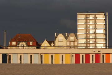 Vue du front de mer au Touquet Paris Plage, dans les Hauts de France, au Nord de la France. Alignement de portes colorées de cabines de bain.. Ciel gris bleu en arrière plan. Photo prise en mai 2024.