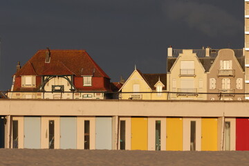 Vue du front de mer au Touquet Paris Plage, dans les Hauts de France, au Nord de la France. Alignement de portes colorées de cabines de bain.. Ciel gris bleu en arrière plan. Photo prise en mai 2024.