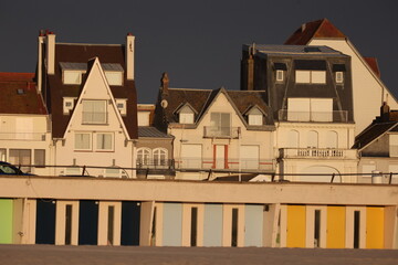 Vue du front de mer au Touquet Paris Plage, dans les Hauts de France, au Nord de la France. Alignement de portes colorées de cabines de bain.. Ciel gris bleu en arrière plan. Photo prise en mai 2024.