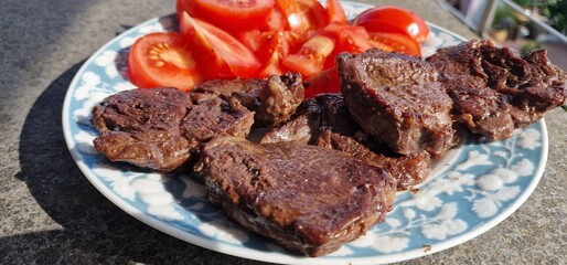 three sliced ​​steak pieces on a plate with tomatoes
