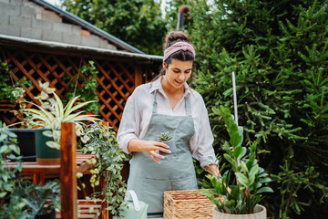 Young woman taking care of plants with water can and mister in garden