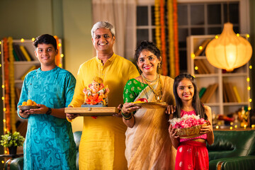 Indian family welcoming Ganpati idol Ganesh on Chaturthi in traditional attire
