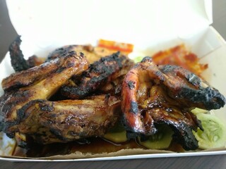 A mouth-watering close-up of grilled chicken wings with a perfectly charred and glazed texture. The crispy skin and juicy meat are served on a bed of fresh vegetables.