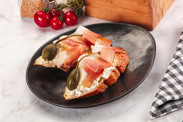 Bruschetta with jamon and caper berries