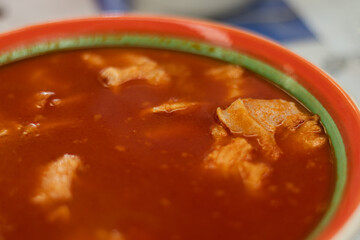 A traditional Mexican beef stomach menudo soup, with a rich red broth and tender chunks of beef in a bowl from an authentic Mexican food restaurant