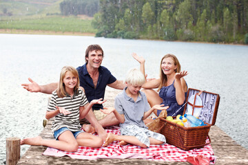 Happy family, picnic and relax with rain outdoor at lake to celebrate, carefree or people laugh on...