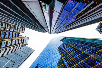 Glass skyscrapers and modern buildings with glass facades seen from below pointing to the sky in...