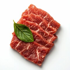 Obraz premium Raw Beef Slices with Green Leaf Garnish on White Background