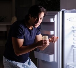 Man breaking diet at night near fridge