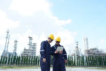 Two male engineers wearing helmets stand talking and inspecting oil system for leaks working...