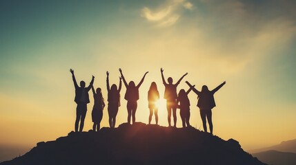 Silhouettes of people raising their hands on a mountaintop during sunset.
