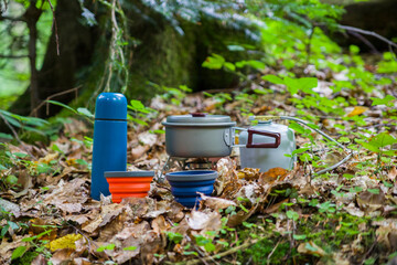 Coffee pot and metal cup on a large stone against the background of a mountain river. Coffee pot on a stone slab against a blurred background of nature.