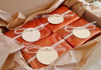 Christmas gifts red color boxes jute ribbon mockup tags, winter wedding favors handmade souvenirs, homemade crafts party presents, natural soap bars, brown craft paper background