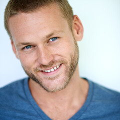 Fototapeta premium Happy, portrait and man in studio with confidence, casual fashion and creative career in design. Smile, face and young professional with cool pride, gen z style and fun laughing on white background