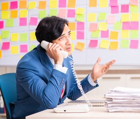 Young handsome employee with many conflicting priorities