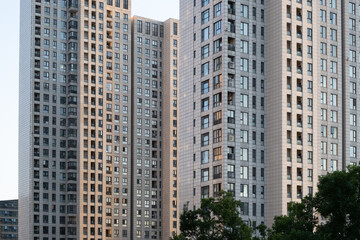 A row of tall, modern high-rise residential apartment buildings with many windows. A high-density urban neighborhood in China. Concept of real estate, housing oversupply crisis,and property investment © Doublelee