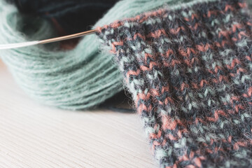 Colourful yarn ball with knitted sock and knitting needles. Alpaca and wool threads with beautiful knitting pattern. Woven crochet close up. Knitting hobby. Knitwear concept. Needlework background. 