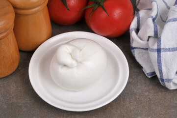 Burrata dans une soucoupe à côté de tomates fraîches vue de dessus