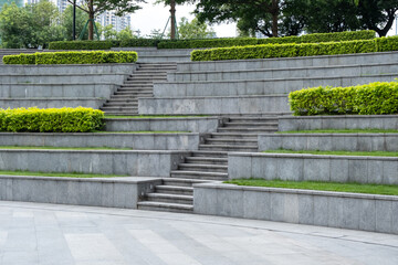 A series of terraced steps made of gray concrete, used as an amphitheater or outdoor seating area,...