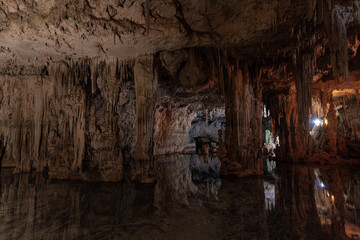 Large cave with large columns and their reflection in the water at the bottom of the Neptune's Grotto in Sardinia, Italy, with artificial lighting and without people © Gustavo Muñoz