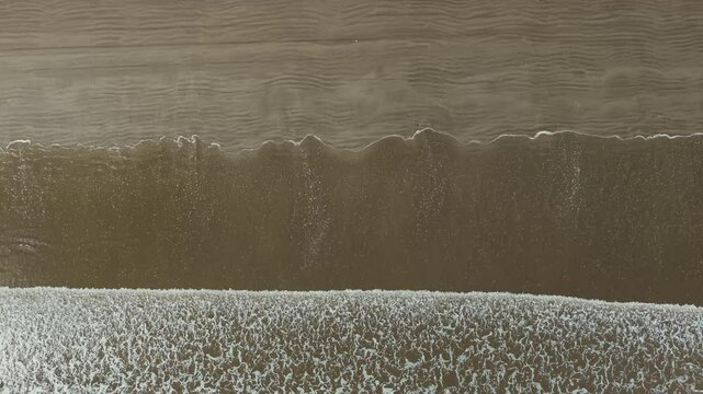 Barrido de olas blancas que crean un efecto de s&aacute;banas en la arena que es captado por un drone en 4k. Este espect&aacute;culo natural se crea desde las alturas y toca la arena amarilla, azul y atardeceres.
