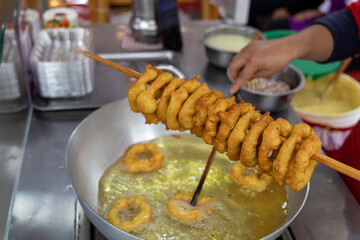 A woman is cooking picarones in a pan