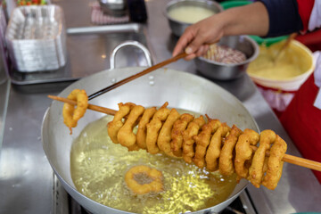 A woman is cooking picarones in a pan