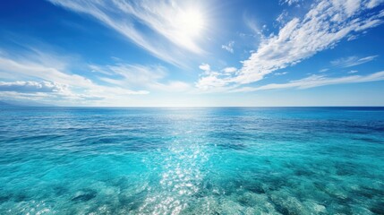 Obraz premium Bright sunlight dances on the calm azure waters, stretching towards the horizon, with clouds lightly adorning the sky above