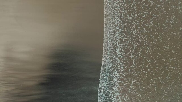 Barrido de olas blancas que crean un efecto de s&aacute;banas en la arena que es captado por un drone en 4k. Este espect&aacute;culo natural se crea desde las alturas y toca la arena amarilla, azul y atardeceres.