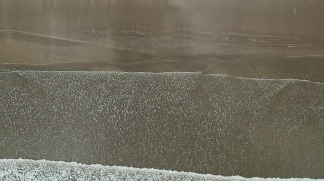 Barrido de olas blancas que crean un efecto de s&aacute;banas en la arena que es captado por un drone en 4k. Este espect&aacute;culo natural se crea desde las alturas y toca la arena amarilla, azul y atardeceres.