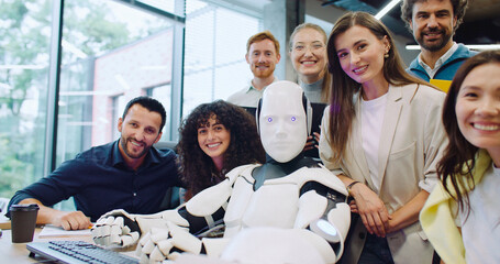 Multi-ethnic group of people surrounding robot. Giving command to press specific key on keyboard in...