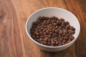 chocolate cereal breakfast in white bowl on wood table
