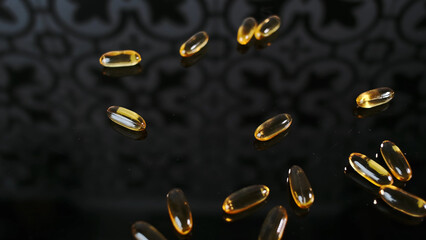 Bunch of yellow capsules pills scattered on a black surface Vitamin D3 production. Concept of...